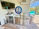 Outdoor kitchen with stainless steel grill, mini refrigerator, sink and television in screened-in patio at 10179 Milky Way Cir, Sarasota, FL 34241