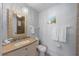 Well-lit bathroom featuring a vanity with stone countertop, and a decorative framed mirror at 110 Oak Ave # A, Anna Maria, FL 34216