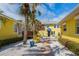 Quaint yellow home with a welcoming brick walkway, manicured landscaping, and inviting outdoor seating at 110 Oak Ave # A, Anna Maria, FL 34216