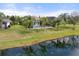 Backyard view from the pond, featuring a screened-in pool, lush lawn, and mature palm trees at 11742 Forest Park Cir, Bradenton, FL 34211