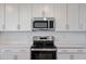 Close-up of the kitchen featuring stainless steel appliances, white cabinets, and modern countertops at 12180 Wellen Golf St # 302, Venice, FL 34293