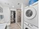 Bright bathroom features tiled walk-in shower, toilet, floating vanity, and stacked washer and dryer, with walk-in closet at 1709 N Tamiami Trl # 422, Sarasota, FL 34234