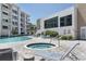 Community pool and jacuzzi with condo building and clubhouse in background at 1709 N Tamiami Trl # 422, Sarasota, FL 34234