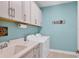 Functional laundry room with white cabinets, a sink, and modern appliances for efficient laundry tasks at 17842 Cherished Loop, Bradenton, FL 34211