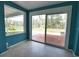 Living room showcasing sliding glass doors with backyard and waterfront views, tile flooring, and blue walls at 221 Laurel E Rd, Nokomis, FL 34275