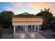 Unique stilt house with a green roof and shutter details, surrounded by lush greenery and a colorful sky at 313 Magnolia Ave, Anna Maria, FL 34216