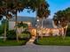 Home's exterior has a brick walkway, mature trees, front lawn, and festive string lights at 3648 Beneva Oaks Blvd, Sarasota, FL 34238
