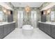 A luxurious bathroom features dual vanities, a soaking tub, and separate shower stalls with designer wallpaper at 412 Pheasant Way, Sarasota, FL 34236