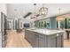 A kitchen features an expansive island with pendant lighting and quartz countertops, seamlessly flowing into the living area at 412 Pheasant Way, Sarasota, FL 34236