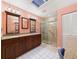 Bathroom with double vanity, granite counters, skylight and tiled walk-in shower with glass door at 4534 La Jolla Dr, Bradenton, FL 34210