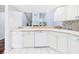 Modern kitchen featuring white cabinetry, tiled backsplash, and a pass-through window at 4534 La Jolla Dr, Bradenton, FL 34210