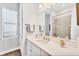 Well-lit bathroom with vanity, quartz counters, framed mirror, and tiled shower at 525 Maraviya Blvd, Nokomis, FL 34275