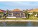 Exterior view from the waterfront of the screened lanai and pool with palm trees in a landscaped yard at 525 Maraviya Blvd, Nokomis, FL 34275