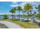 Resort-style pool area with lounge chairs, tables, umbrellas, and palm trees overlooking a serene lake view at 525 Maraviya Blvd, Nokomis, FL 34275