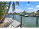 Private boat dock provides easy access to the water, complemented by lush landscaping and clear blue skies at 612 Foxworth Ln, Holmes Beach, FL 34217