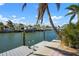 Scenic waterfront view highlighting a private dock, boat lift, and stunning canal waters framed by palm trees at 612 Foxworth Ln, Holmes Beach, FL 34217