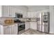 Well-lit kitchen featuring white cabinetry, granite countertops, and stainless steel appliances at 6433 Blue Grosbeak Cir, Lakewood Ranch, FL 34202