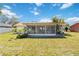 Green backyard showcasing the sunroom addition, set against a backdrop of a blue sky at 6812 19Th W Ave, Bradenton, FL 34209