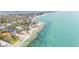 Expansive aerial view of beachfront properties bordering clear turquoise waters along the shoreline, set among mature trees at 7324 Point Of Rocks Rd, Sarasota, FL 34242