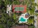 Overhead view of amenities: pool, hot tub, and tennis court enveloped by verdant trees at 7613 4Th W Ave # 7613, Bradenton, FL 34209