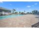 Enjoy a large community pool with palm trees, blue sky, and ample brick patio for lounging around the water at 1218 Spoonbill Landings Cir, Bradenton, FL 34209