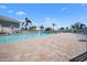 Community pool with brick patio, ample lounge seating, and tropical palm trees at 1218 Spoonbill Landings Cir, Bradenton, FL 34209
