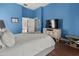 A bright bedroom with a blue accent wall, with a TV set atop a light colored dresser at 1817 91St Nw St, Bradenton, FL 34209