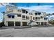 Stunning three-story building with modern architecture, blue awnings, and private garage spaces at 1900 Harbourside Dr # 102, Longboat Key, FL 34228