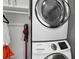 Handy laundry room featuring stacked washer and dryer, storage cabinets, and a convenient cleaning tool at 1900 Harbourside Dr # 102, Longboat Key, FL 34228