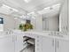 Elegant main bathroom showcasing double sinks, modern lighting, an expansive mirror and white cabinetry at 1900 Harbourside Dr # 102, Longboat Key, FL 34228