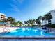 Expansive community pool with inviting clear water surrounded by swaying palm trees under a sunny sky at 1900 Harbourside Dr # 102, Longboat Key, FL 34228