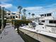 Lovely waterfront view of a modern boat docked at the pier, featuring a house backdrop with palm trees and blue sky at 1900 Harbourside Dr # 102, Longboat Key, FL 34228