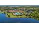 Stunning aerial view of community amenities including a resort-style pool, clubhouse, and tennis courts by the lake at 24068 Canterwood Way, Venice, FL 34293