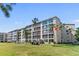 A condo with large windows, a well-manicured lawn, and palm trees on a sunny day at 3664 Lake Bayshore Dr # K323, Bradenton, FL 34205