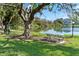 Lush outdoor area with mature trees, picnic table, and tranquil water view at 3664 Lake Bayshore Dr # K323, Bradenton, FL 34205