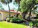 Charming single-story home with a terracotta tile roof and lush, mature landscaping with palm trees and flowering shrubs at 3818 Sun Eagle Ln, Bradenton, FL 34210