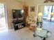 Cozy living room featuring a television, rattan chair and view to the lanai at 3818 Sun Eagle Ln, Bradenton, FL 34210