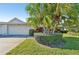 Home's exterior showcasing lush landscaping, mature palms, manicured shrubbery, and a spacious two-car garage at 3880 Wilshire Cir # 28, Sarasota, FL 34238