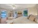 Spacious bedroom with hardwood floors, white walls, french doors leading to the pool, and a sunset image on the television at 7715 Westmoreland Dr, Sarasota, FL 34243