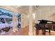 Elegant living room with a grand piano and french doors opening to a landscaped backyard and pool area at 7715 Westmoreland Dr, Sarasota, FL 34243