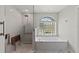 Bright bathroom with a tiled walk-in shower, soaking tub, glass block window, and accessibility features at 8106 Arlewood Cir, Port Charlotte, FL 33981