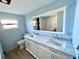 Bathroom featuring a double sink vanity with a marble countertop and a large mirror reflecting the shower area at 8219 Drew St, Englewood, FL 34224