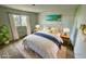 Cozy staged bedroom with large bed, area rug, two side tables, lamps, beach wall art, and a bright window at 8219 Drew St, Englewood, FL 34224