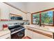 Bright kitchen features white cabinets, a stainless steel microwave, and a window overlooking the backyard at 8270 Manasota Key Rd, Englewood, FL 34223