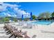 Community pool area with lounge chairs and tables with umbrellas on a sunny day with scattered clouds at 9570 High Gate Dr # 1722, Sarasota, FL 34238
