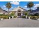 The front exterior of Rosedale Golf and Country Club clubhouse with beautiful landscaping, palm trees, and stone walkway at 9734 51St Terr E, Bradenton, FL 34211