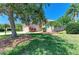 Beautiful front yard featuring lush lawn, tropical plants, and mature trees, adding privacy and curb appeal at 9734 51St Terr E, Bradenton, FL 34211