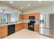 Functional kitchen with stainless steel appliances, natural wood cabinetry, tile flooring, and a breakfast bar at 9767 50Th Street E Cir, Parrish, FL 34219