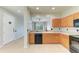 Well-lit kitchen with a breakfast bar, black appliances, wood cabinets, and a view into the living area at 9767 50Th Street E Cir, Parrish, FL 34219