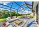 Inviting screened porch with comfortable seating, dining set, and serene views of the green backyard and blue sky at 9767 50Th Street E Cir, Parrish, FL 34219